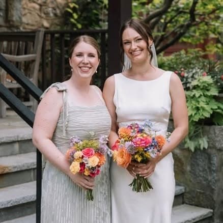 A bride and her attendant holding brightly coloured garden bouquets.