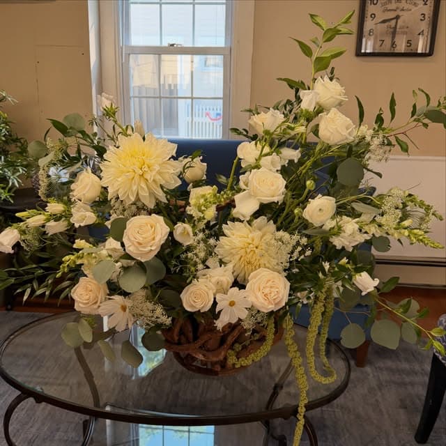 A cream and white basket arrangement with dahlias, roses and trailing amaranthus.